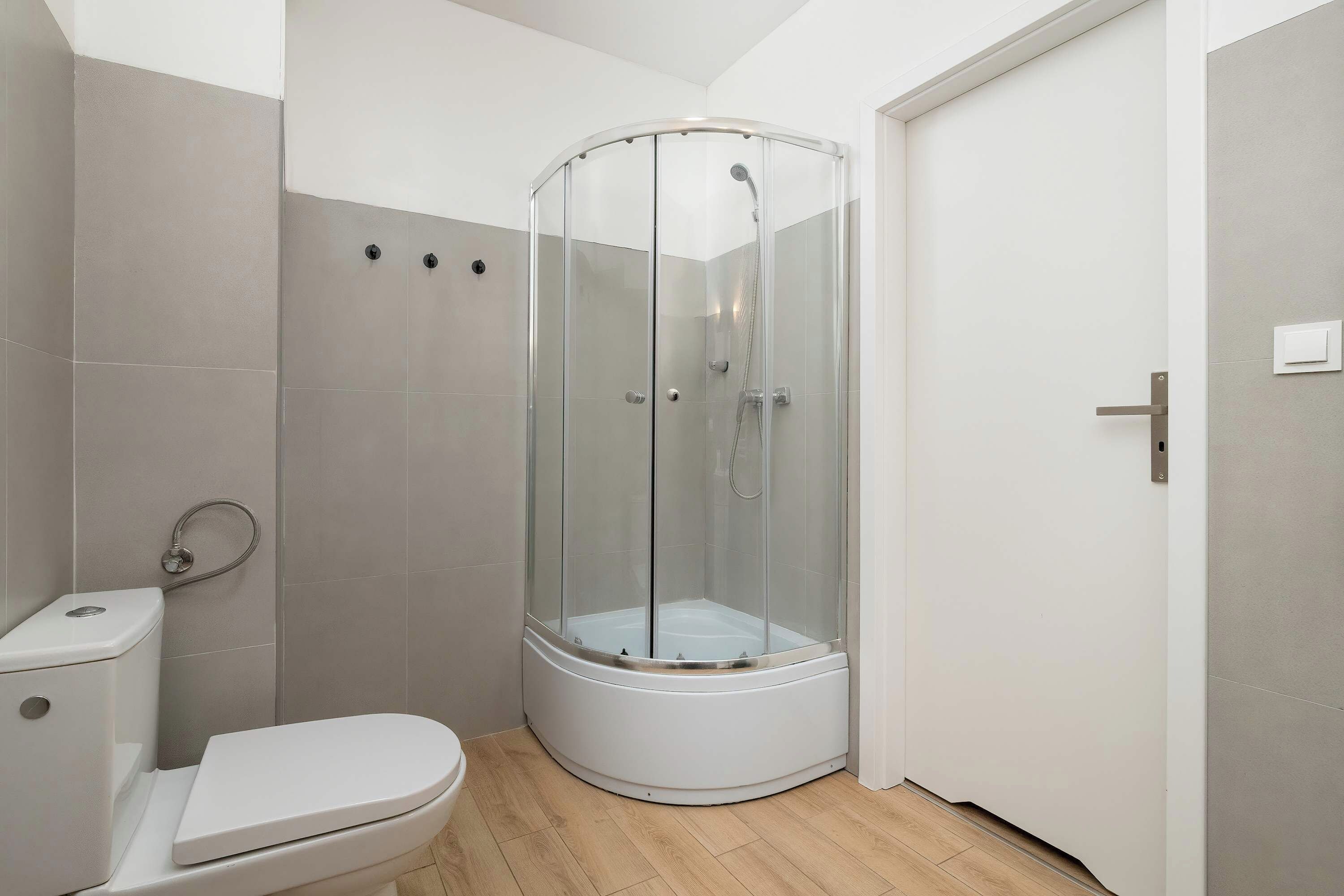 Een badkamer met een wit toilet, een douchecabine en een deur.