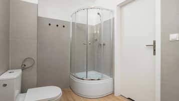 Een badkamer met een wit toilet, een douchecabine en een deur.