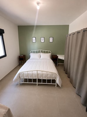 A bedroom with a bed, a nightstand, a window, and a curtain. - HOUSE WITH A SWIMMING POOL, AIR CONDITIONING, AND A LARGE GARDEN (Vierzon)