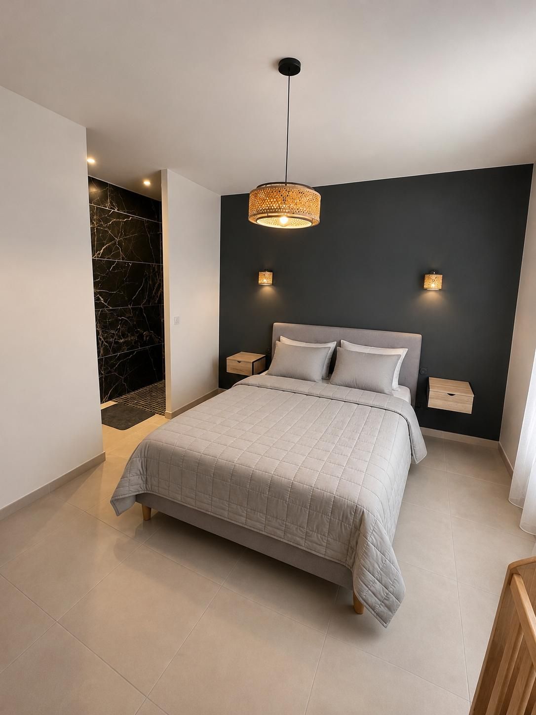 Un dormitorio moderno con cama, mesitas de noche, lámpara colgante y una pared de acento oscura.