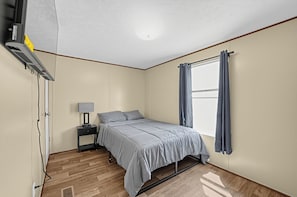 A bedroom with a bed, bedside table, lamp, and a window with curtains. - 
Fully Furnished 3BR/2BA Monthly Workforce Housing Near Holly Ridge Data Center (Monroe)
