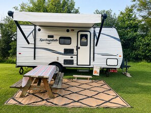 A recreational vehicle with a covered sleeping area, a picnic table, and a welcome sign. - Cozy Country Escape with all the Amenities, Close to Taylor U, IWU, BSU (Upland)