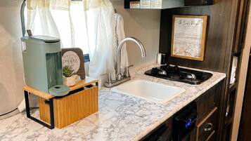 A compact kitchen with a built-in dishwasher, a microwave, and a sink.