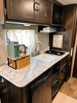 A compact kitchen with a built-in dishwasher, a microwave, and a sink. - Cozy Country Escape with all the Amenities, Close to Taylor U, IWU, BSU (Upland)