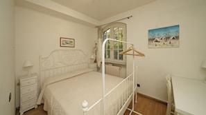 Un dormitorio con una cama individual, un aparador, una ventana con cortinas y un cuadro en la pared.
