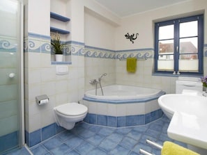 A bathroom with a bathtub, toilet, and sink. - New Row 43 Villa Regulus Ground Floor (Zingst)