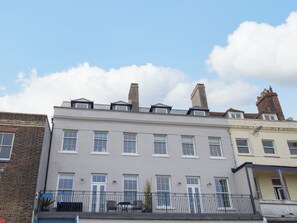 A multi-story residential building with a flat roof, multiple windows, and a balcony with outdoor furniture. - 4 The Beaches (Weymouth)