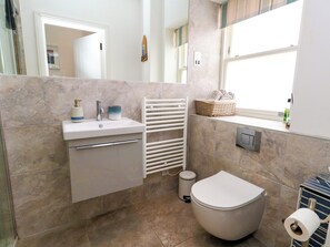 A bathroom with a toilet, sink, and a window. - 4 The Beaches (Weymouth)