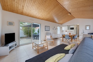 Una sala de estar moderna con un sofá, una mesa de centro, un televisor y un comedor con sillas y una mesa.