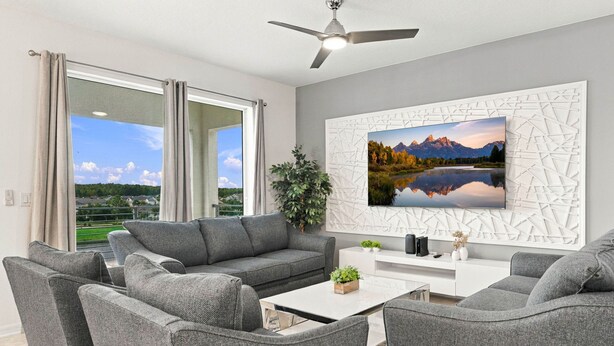 Ein modernes Wohnzimmer mit einer grauen Sofagarnitur, einem Couchtisch und einem großen Landschaftsbild an der Wand.