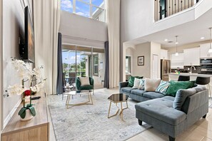 A spacious living room with a grey sofa, a coffee table, and a TV mounted on the wall. - Perfect Family Escape, Pool, Themed Rooms (Four Corners)