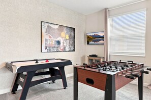 A room with a foosball table, a television, and artwork on the wall. - Perfect Family Escape, Pool, Themed Rooms (Four Corners)