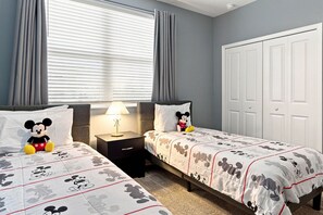 A hotel room with two beds, each with Mickey Mouse-themed bedding, a nightstand with a lamp, and a wardrobe. - Perfect Family Escape, Pool, Themed Rooms (Four Corners)