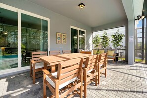 Eine Außenpatio mit Holztisch und Stühlen, eine Glastür zum Pool und ein Schild mit den Poolregeln.