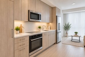 Una cocina moderna con armarios de madera, un microondas Bosch, un refrigerador de acero inoxidable y un horno empotrado.