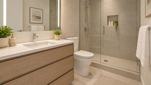 Een moderne badkamer met een douchecabine van glas, een wastafel met houten opbergmeubel, en een toilet.