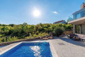 A swimming pool with a sunlit sky, a stone wall, and outdoor furniture. - Villa Bootshaus mit Pool und Meerblick (Vrbnik)