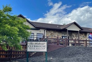 A building labeled 'The Hideout Clubhouse Tenth Hole Pub' with a stone facade and a wooden fence in front. - Walk to Pool & Lake! 5BR Family Hideout Retreat With AC (Lake Ariel)