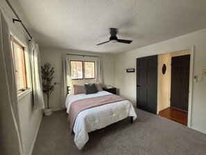 A bedroom with a bed, a ceiling fan, a potted plant, and a door. - Walk to Pool & Lake! 5BR Family Hideout Retreat With AC (Lake Ariel)