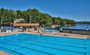 Une piscine avec des couloirs de nage bien délimités, un poste de surveillance pour les sauveteurs et une vue sur un lac.