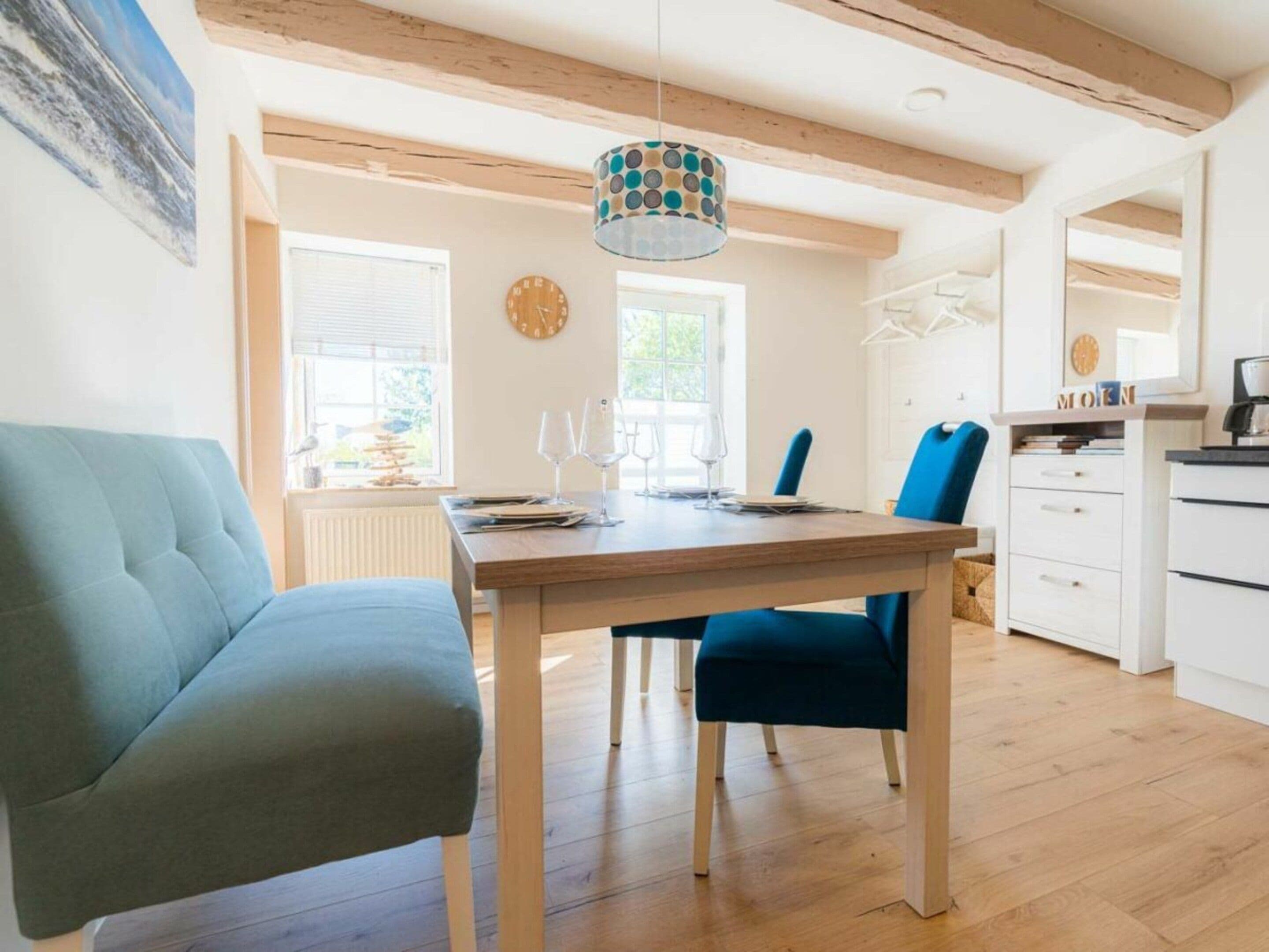 Un comedor con una mesa de madera, sillas azules y una lámpara colgante.
