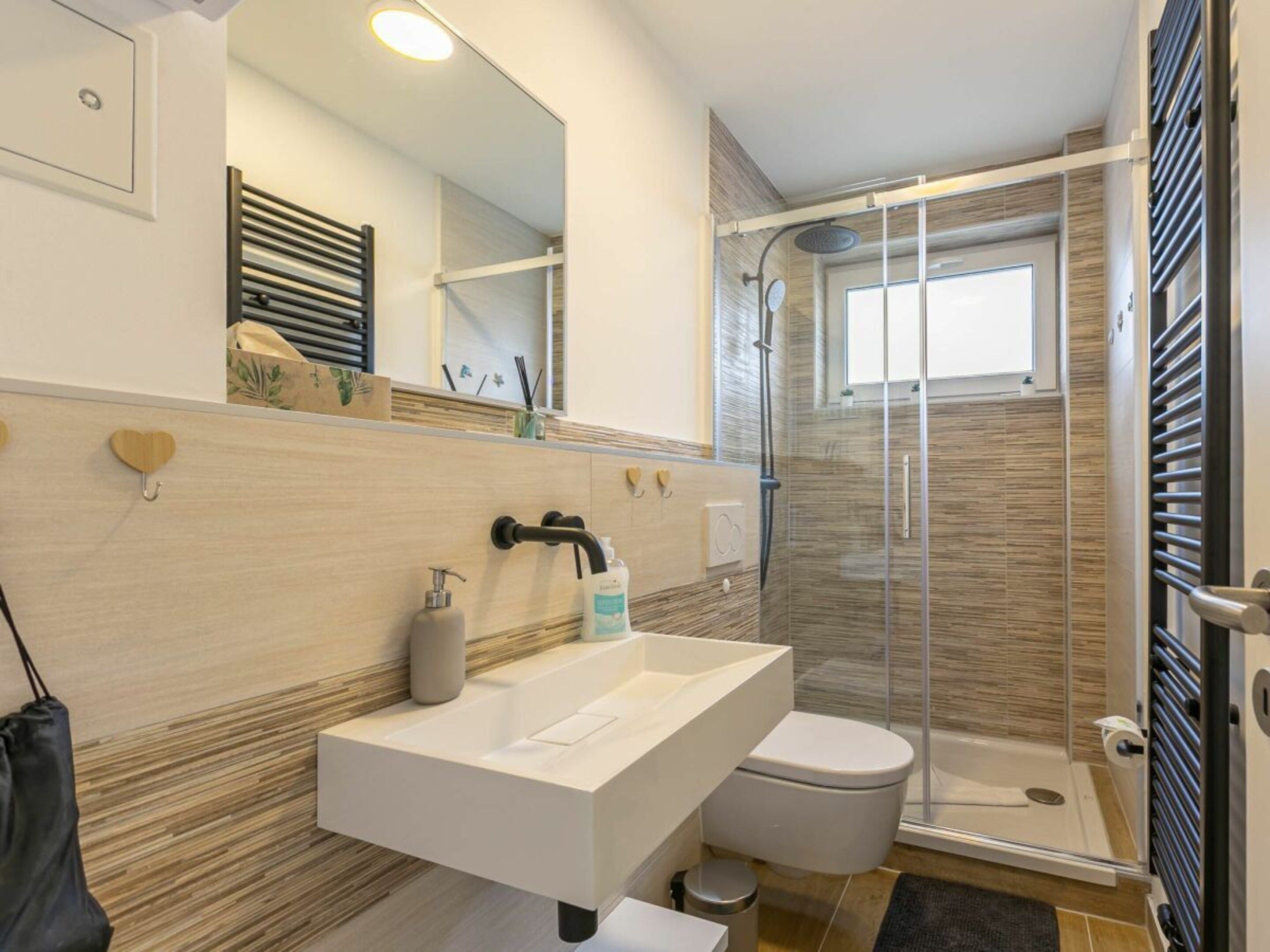 Um banheiro moderno com pia branca, vaso sanitário e box de vidro.