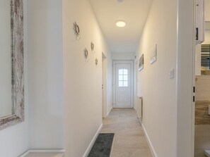 A hallway with a door at the end, a light fixture on the ceiling, and a small rug on the floor. - Apartment 6 "home Port" (St. Peter-Ording)