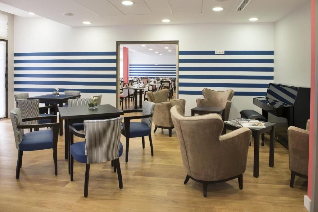 A dining area with striped walls, multiple tables, and chairs.