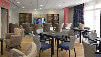Habitación de hotel con comedor, televisión y estanterías.