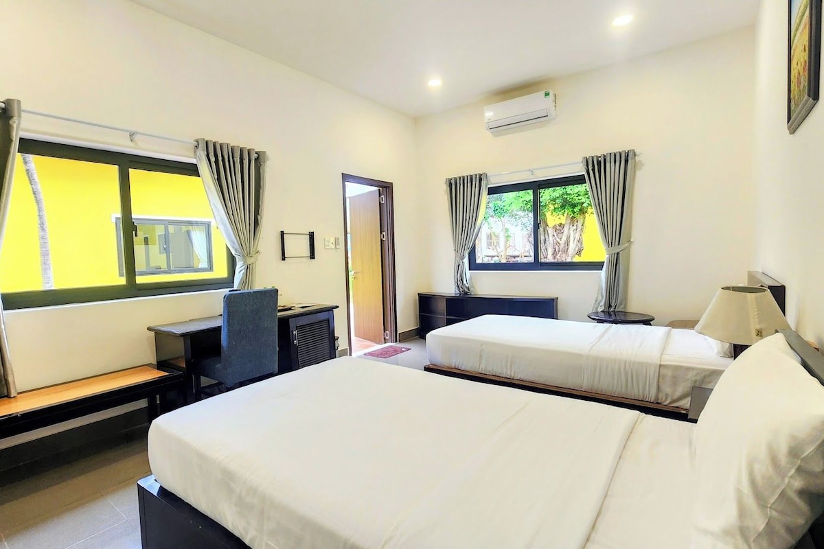 A hotel room with two beds, a desk, and a chair.