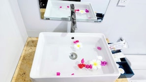 A bathroom sink with a mirror above it, a drain, and a small tray with toiletries. - Sun Resort & Villa (Tien Thanh)