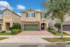 A residential building with a central garage, stone facade, and a symmetrical design. - Themed 8BR Home w/ Private Pool & Custom Game Room (Kissimmee)