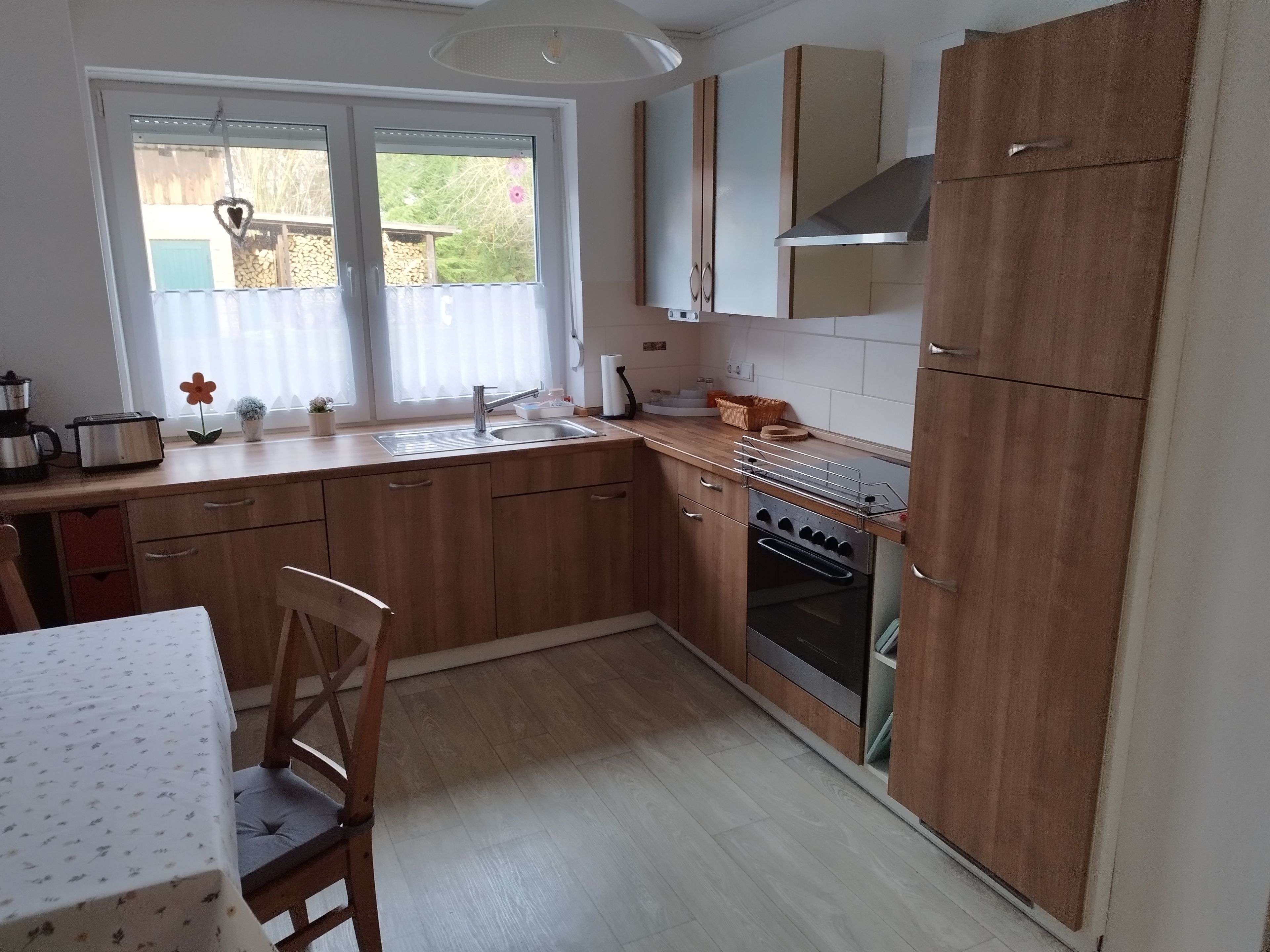 Una cocina con armarios de madera, un lavamanos, una estufa y una ventana con cortinas.
