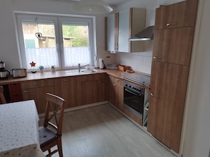A kitchen with wooden cabinets, a sink, a stove, and a window with curtains.