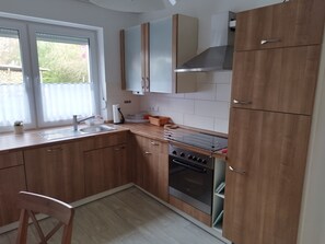 Eine moderne Küche mit Holdekor-Schränken, einem Edelstahlbackofen und einem Fenster mit Vorhängen.
