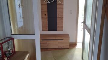A room with a wooden dresser, a hanging ornament, and a door leading to another space.