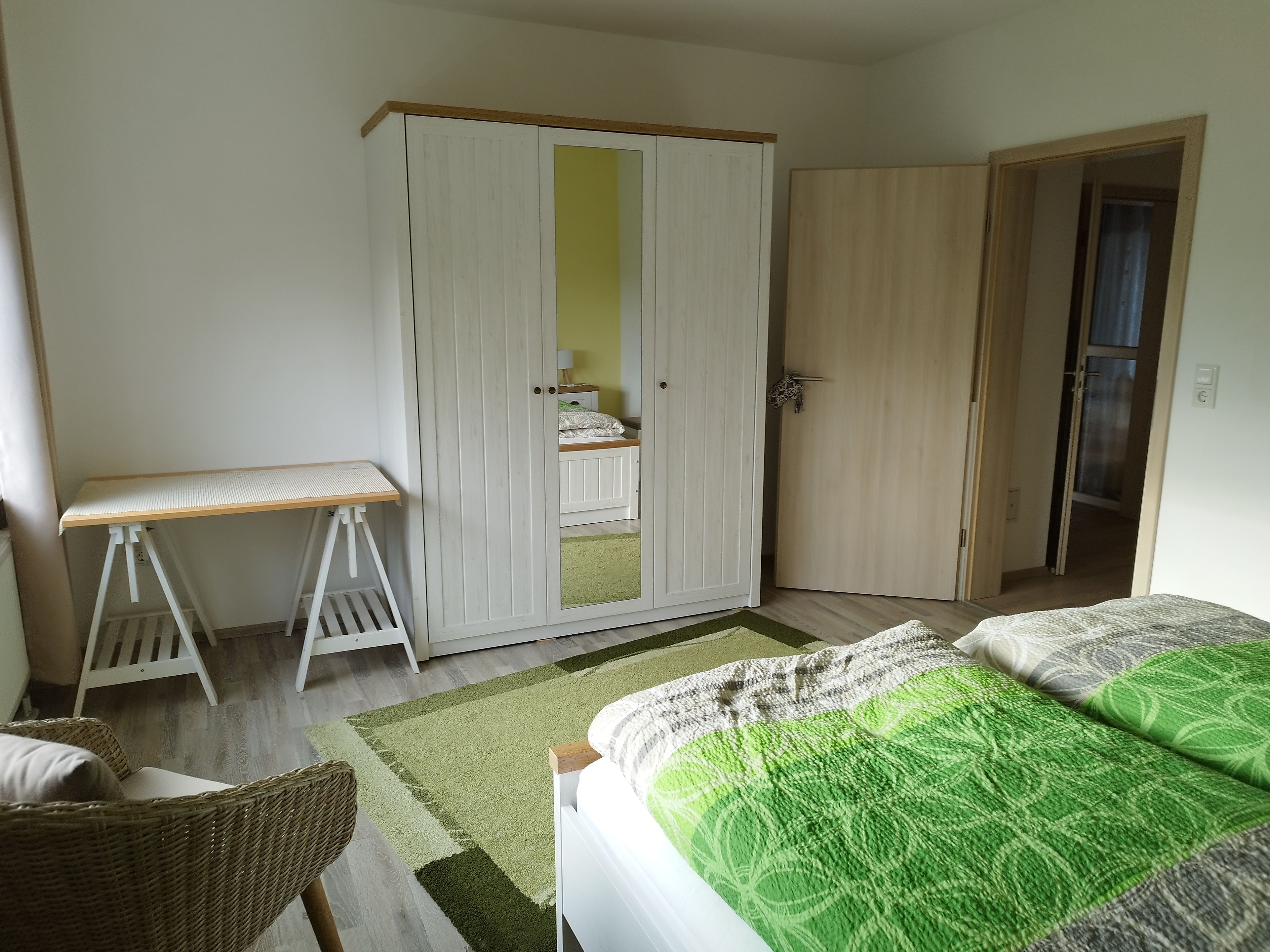 Een slaapkamer met een bed, een kledingkast, een bureau en een stoel.