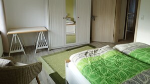 Et soveværelse med seng, skab, skrivebord og stol.