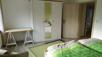 Een slaapkamer met een bed, een kledingkast, een bureau en een stoel.