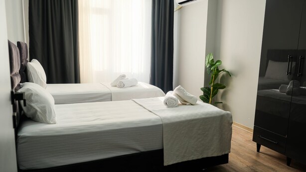 Quarto de hotel com duas camas, uma planta e um guarda-roupa.