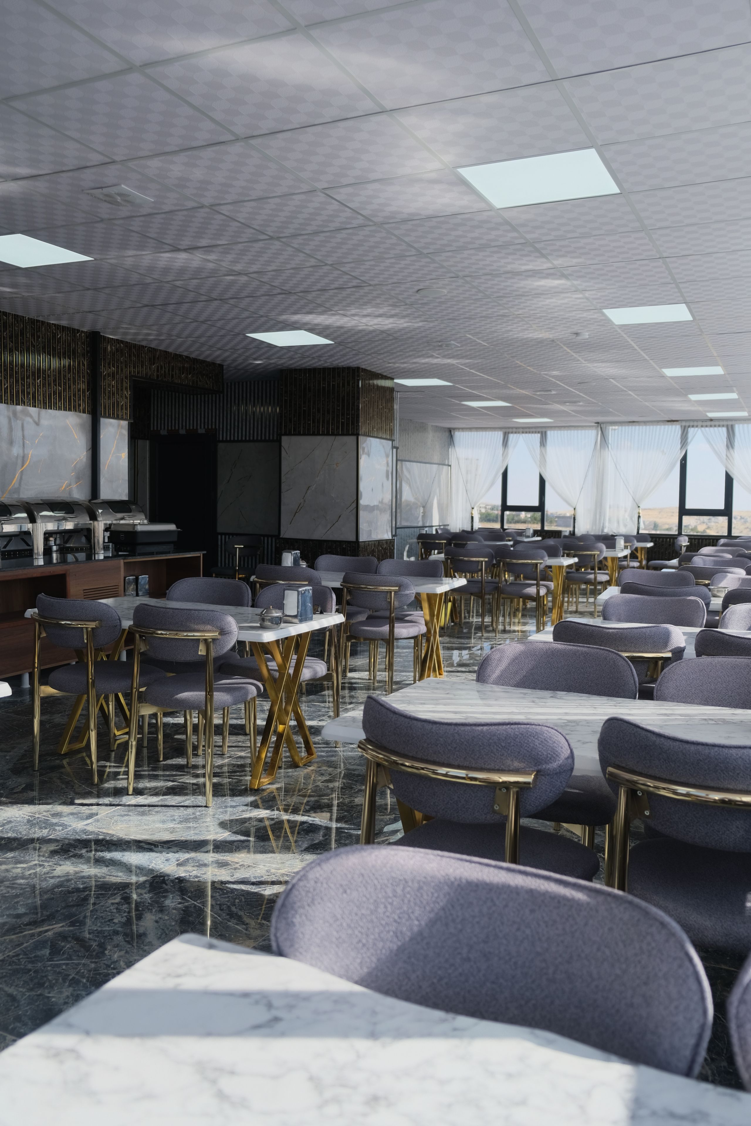 Un salón de conferencias con techo alto, iluminación moderna y vistas al paisaje a través de amplias ventanas.
