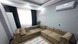 Una sala de estar moderna con un sofá modular, un tapete estampado y un equipo de aire acondicionado en la pared.