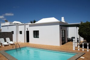 A modern building with a swimming pool, white exterior walls, and a covered patio area. - 3 Bedroom Villa in Playa Blanca (Yaiza)