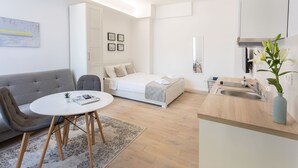 A compact hotel room with a sofa, a bed, a small dining table, and a kitchenette. - Bogoviceva 1b (Zagreb)