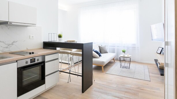 A modern kitchen with a built-in oven and a dining area with a sofa and chairs. - Bogoviceva 1b (Zagreb)