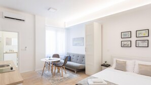 A modern hotel room with a bed, a sofa, a dining table, and a small kitchen area. - Bogoviceva 1b (Zagreb)