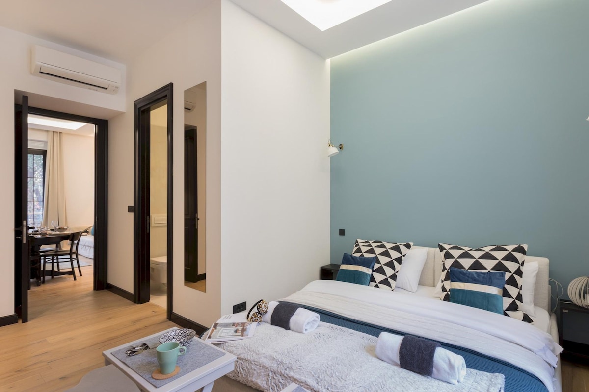 A modern bedroom with a bed, pillows, a bedside table, and a nightstand.