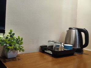 Une petite table sur laquelle se trouve un pot de plante, un plateau avec une théière, des verres et une tasse.