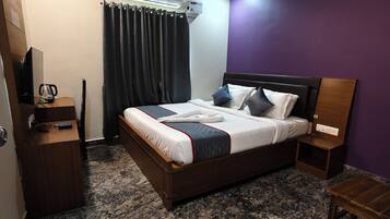 Un dormitorio con cama, escritorio, silla, ventilador de techo y aire acondicionado.