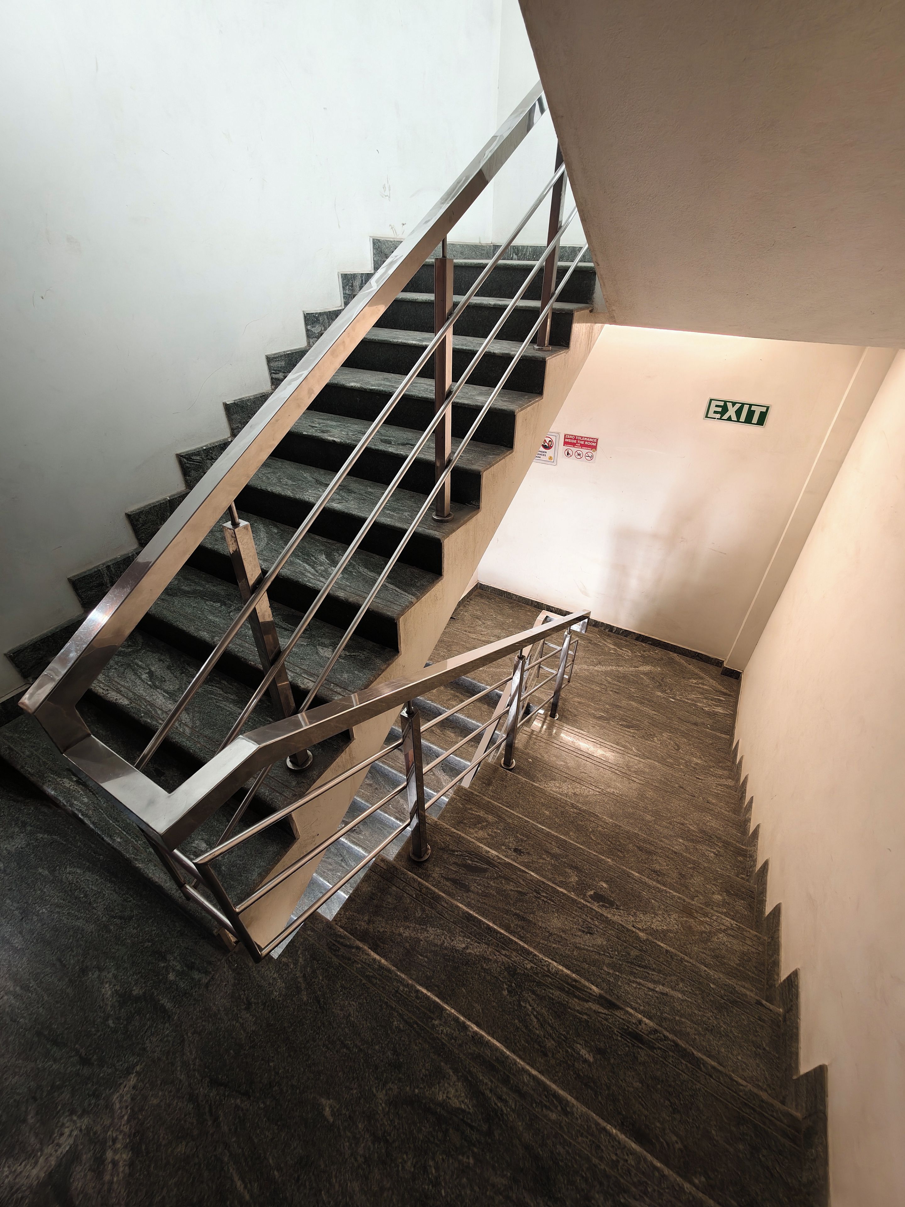 Una escalera con barandillas de metal y un letrero que indica una salida.